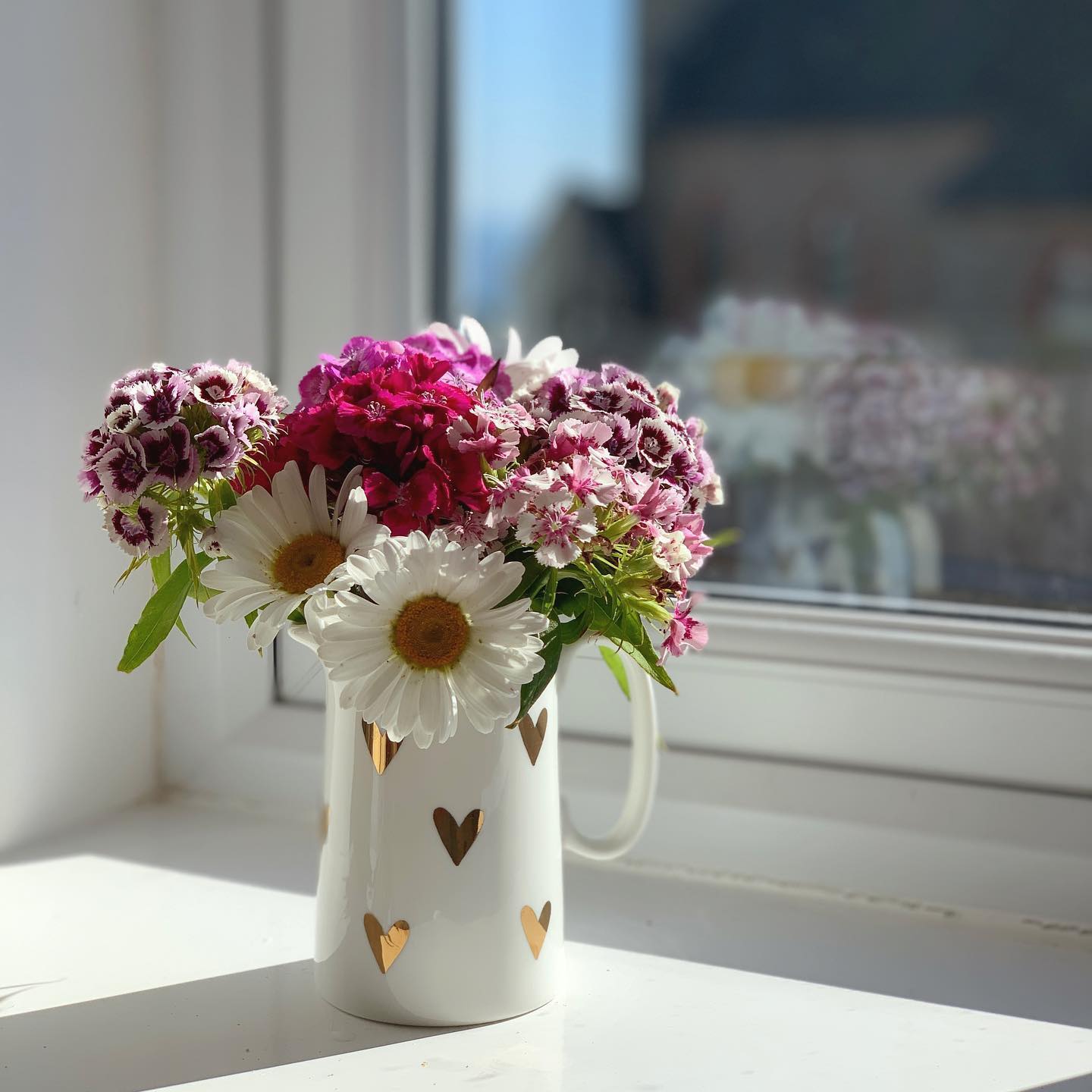 Small gold heart jug holding a posy of flowers