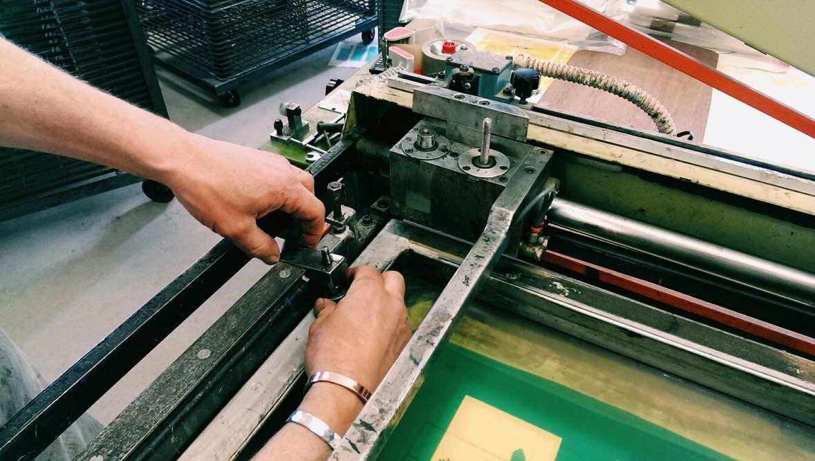 Hands lining up a screen on the printing press